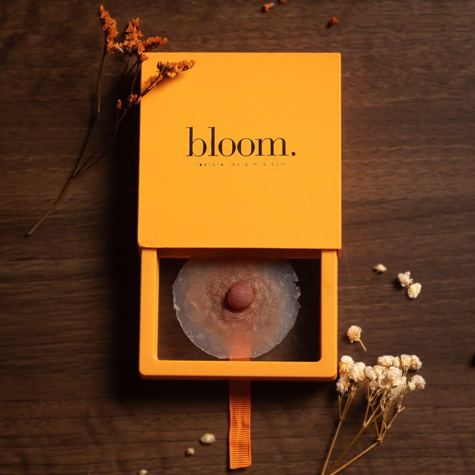 A Bloom Signature piece seen from above in the open drawer of its marigold box, with dried gypsophila on dark wood.