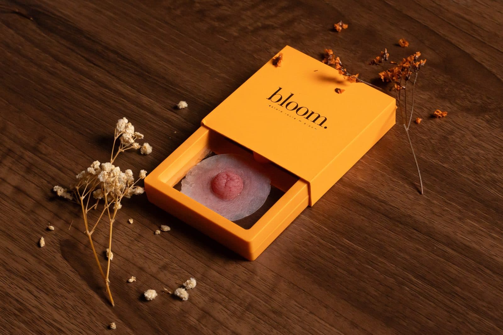 A Bloom piece in a fair shade in its open marigold box on dark wood.