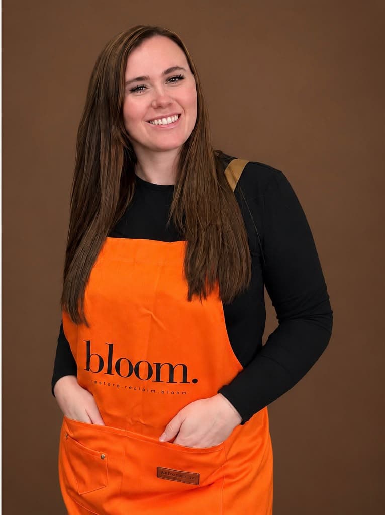 Amanda Jo, Bloom artist in Wallsend, smiling in a marigold Bloom apron.